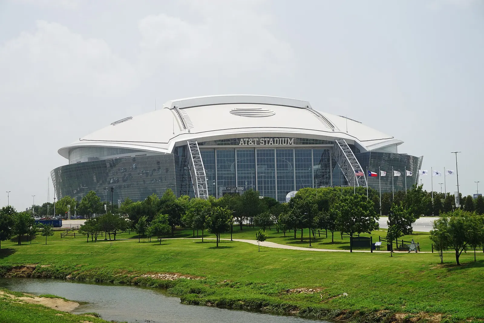 AT&T Stadium in Arlington, Texas beyond a creek and parkland