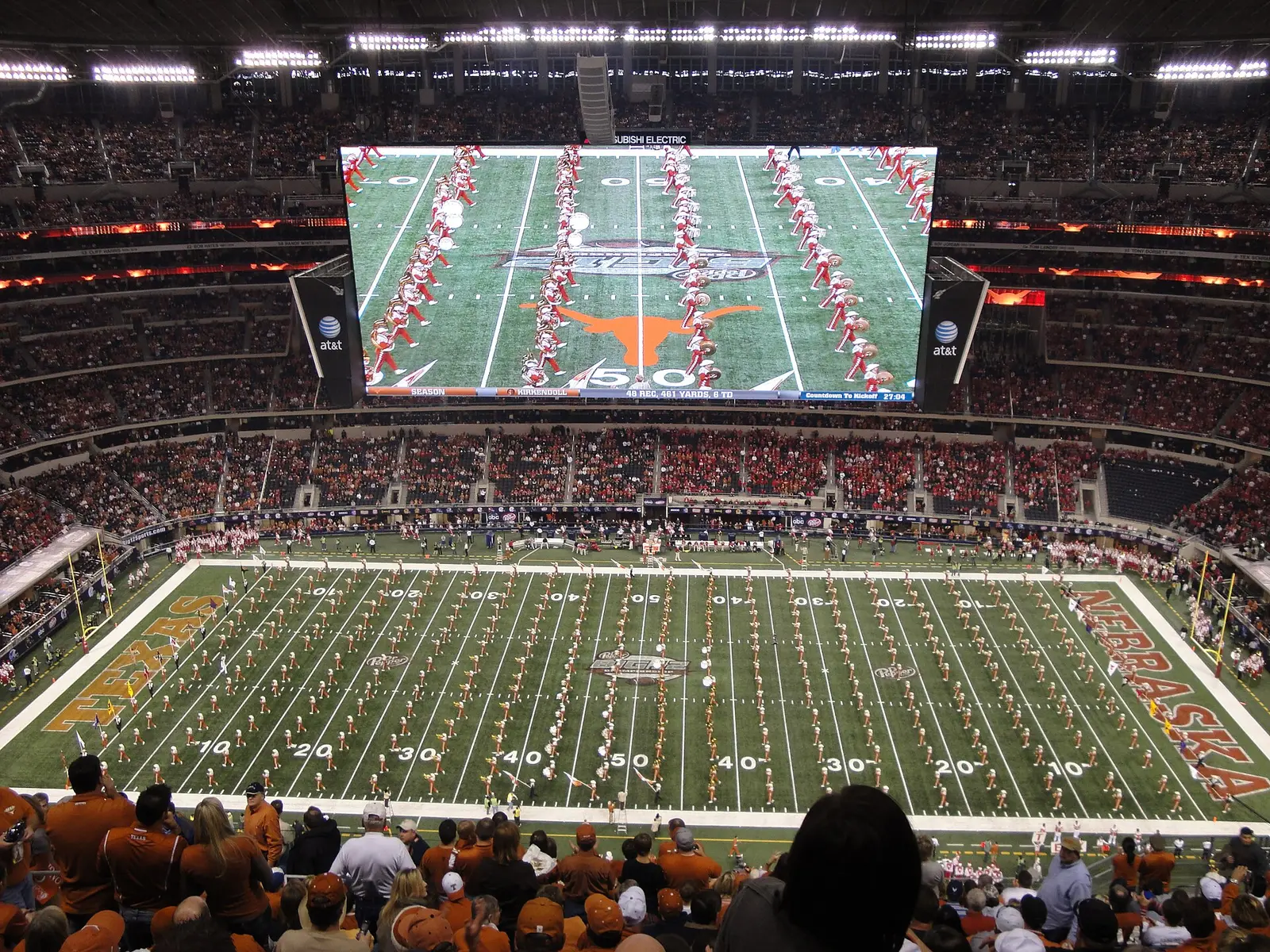 The Texas marching band on the field and video board at an earlier Big 12 Championship game in AT&T Stadium