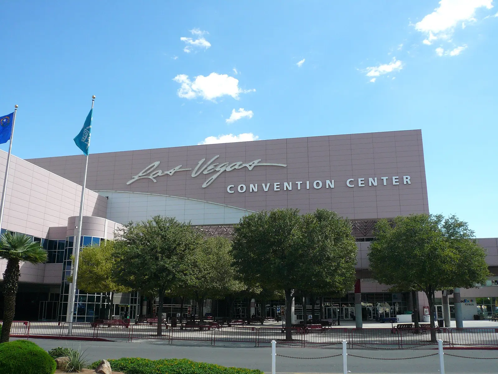 Front of the Las Vegas Convention Center on a sunny day with flagpoles and trees