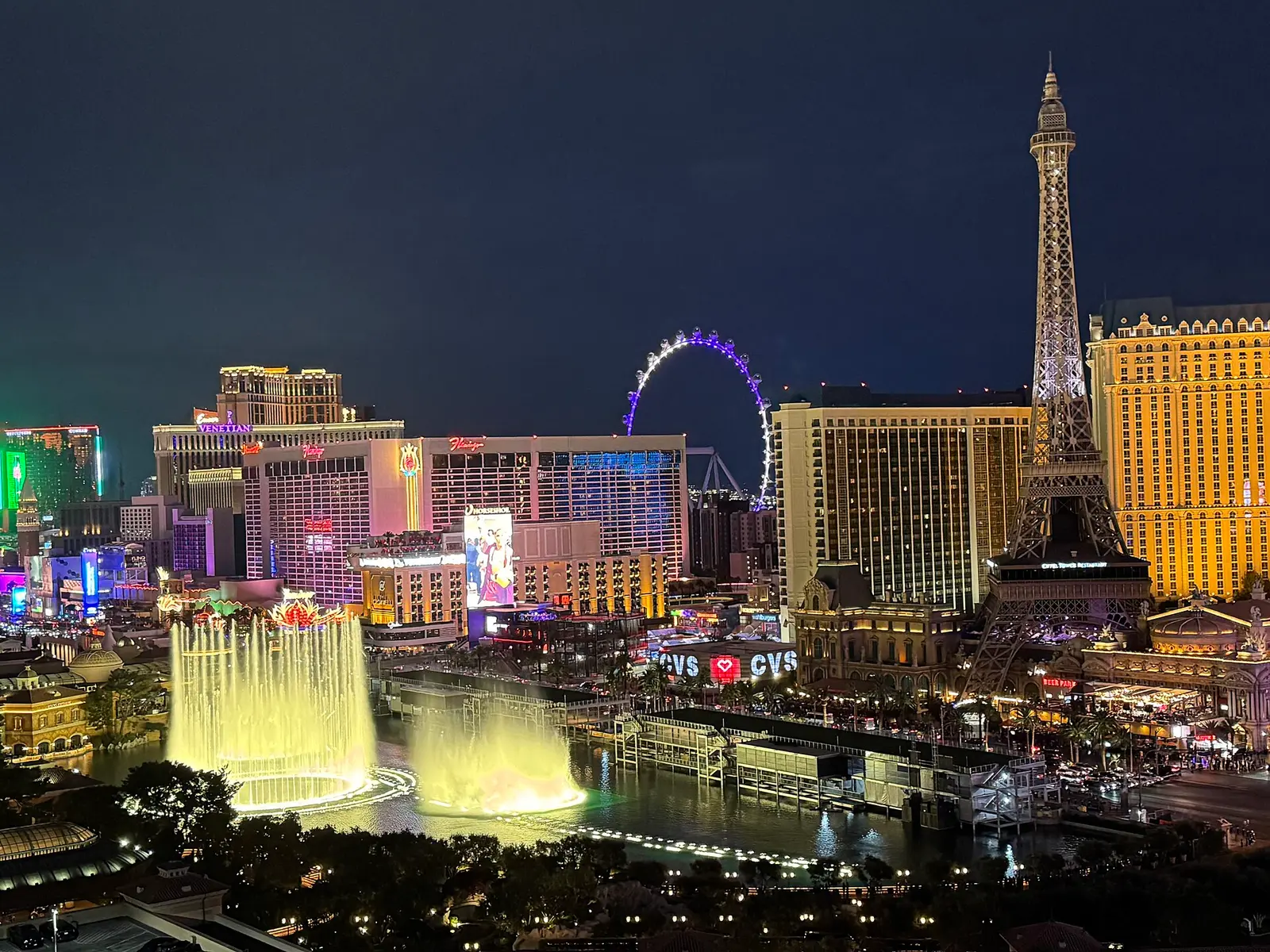 The Las Vegas Strip at night with the Eiffel Tower replica, Bellagio fountains and the High Roller wheel