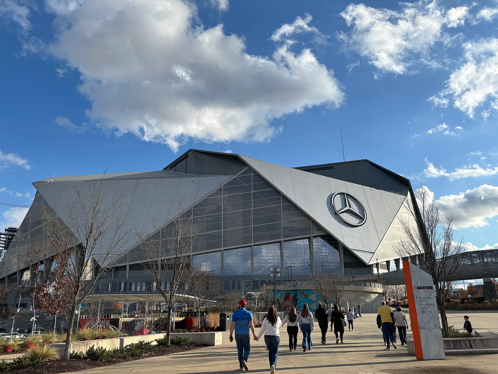 Mercedes-Benz Stadium in Atlanta with its angular roof and glass facade under blue sky