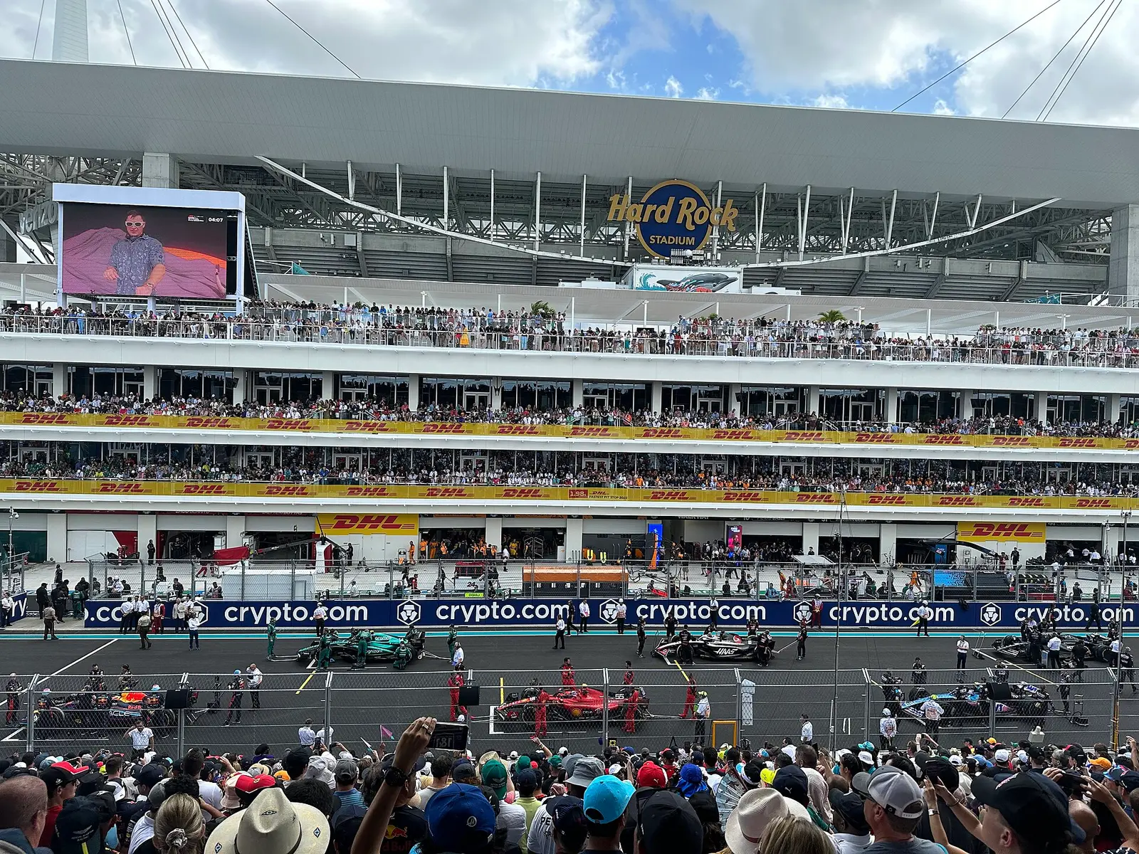 Cars on the grid at the start finish straight of the Miami Grand Prix with Hard Rock Stadium behind